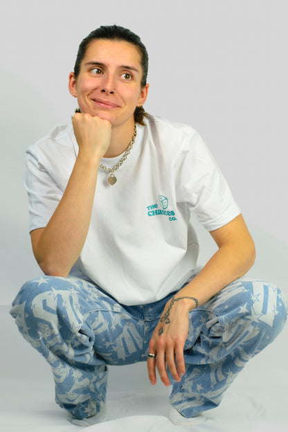 Person wearing a white t-shirt with a green smiley dice logo and the chances co written next to it. Knelt in front of a plain background