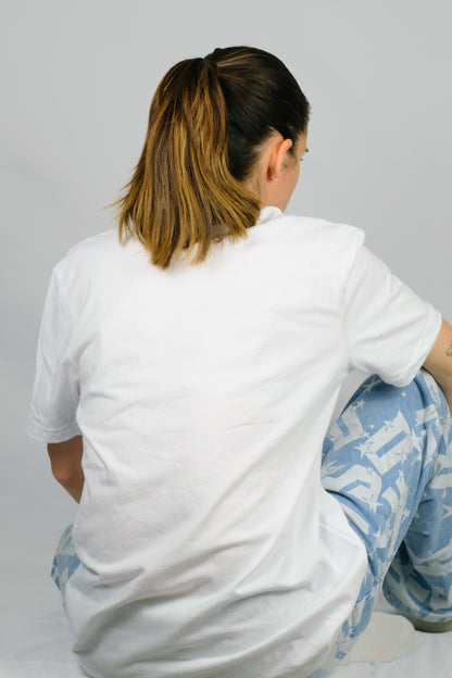 Person wearing a white Chances Clothing t-shirt and light blue pants with text sitting on a grey background