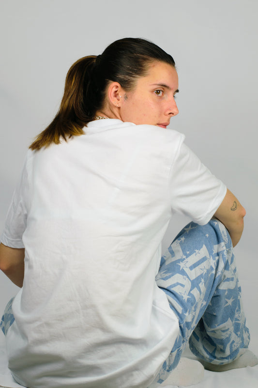 Person wearing a white Chances Clothing t-shirt and light blue pants with star patterns on a plain background