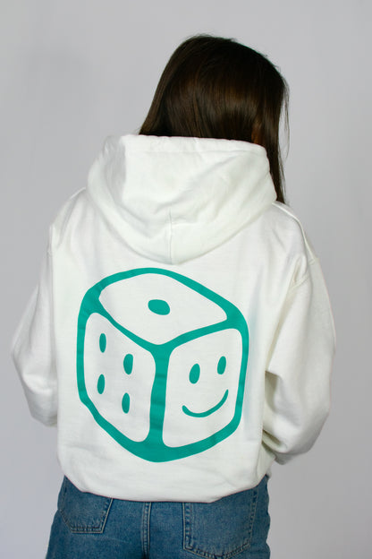 Person wearing a white hoodie with a teal smiley dice design on the back against a grey background