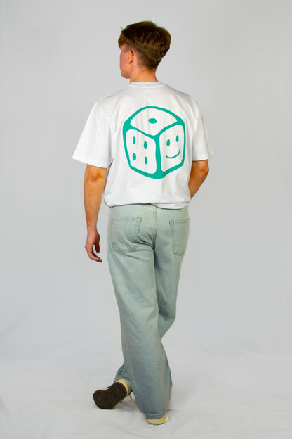 Person wearing a white t-shirt with a green smiley dice design on the back, standing against a plain background.