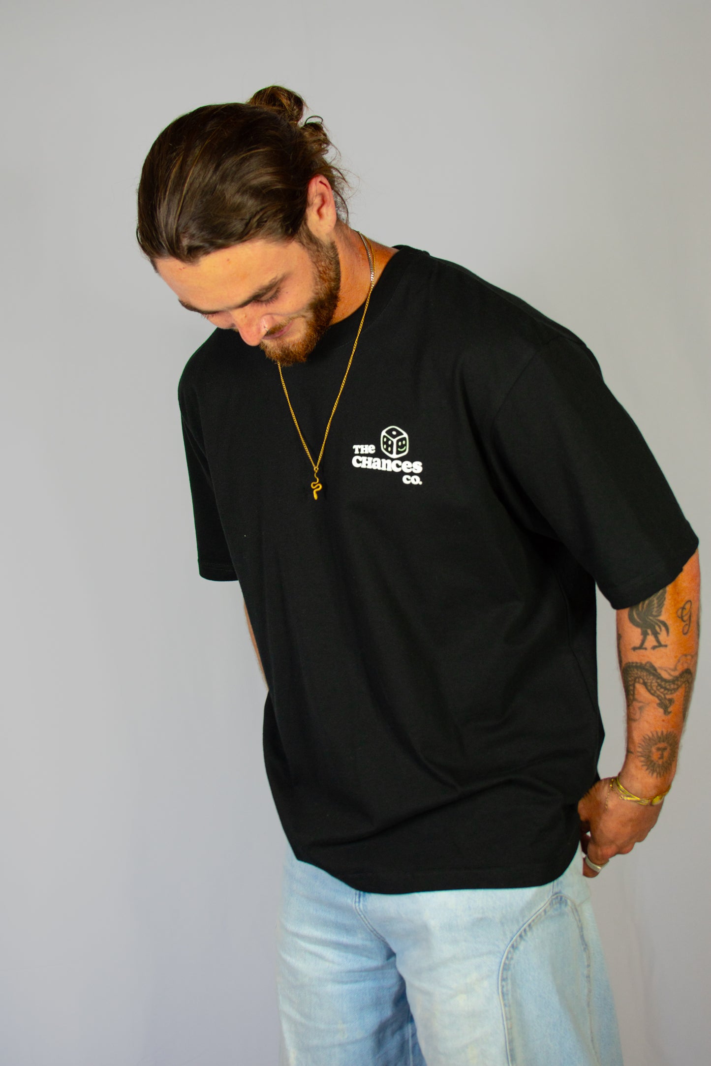 Man wearing a black t-shirt with a white dice logo on a grey background