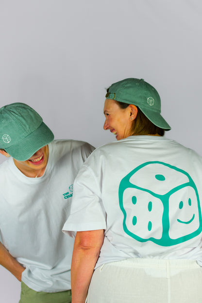 Two people wearing green caps and white t-shirts with a smiley face dice logo design on both the T-Shirts and Caps.