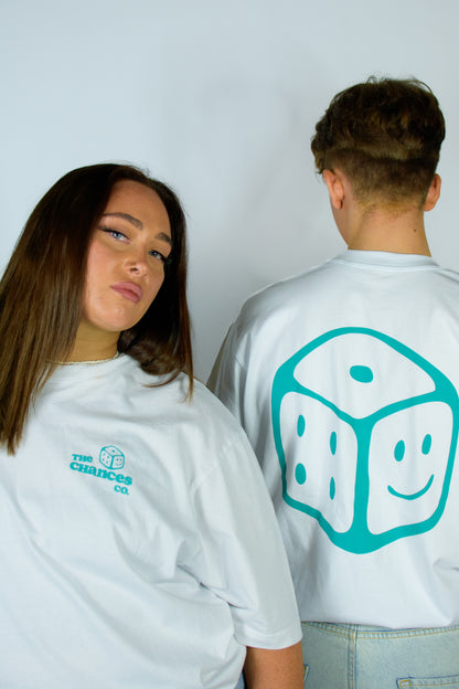 Two people wearing white t-shirts with logos, one on the front and one on the back. Logo on back is a green smiley dice and "The Chances Co" is written on front of T-shirt with smiley dice too.